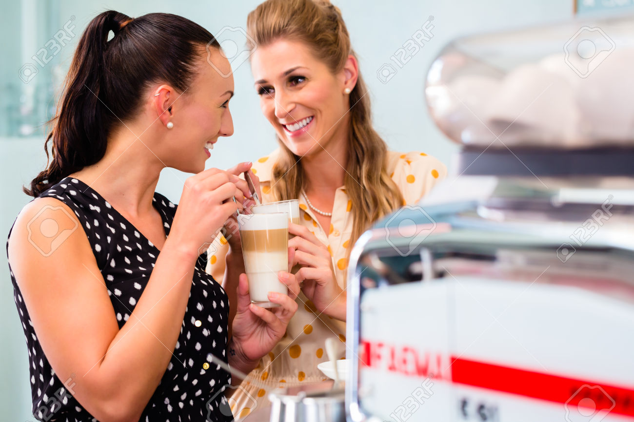 Girl friends drinking latte macchiato in coffee bar