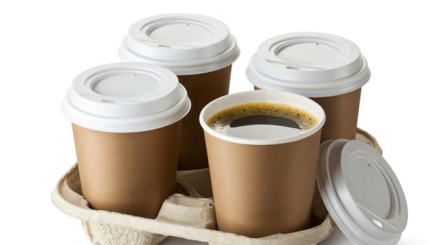 Four take-out coffee in holder. One cup is openend.